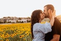 Young couple in love kissing her nose in the sunflower field at sunset