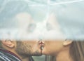 Young couple in love kissing under the rain with transparent umbrella - Handsome bearded man and woman enjoying havig tender