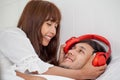 Young couple in love looking at each other lying together on white bed Romantic moment in morning .woman wearing headphones for Royalty Free Stock Photo