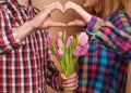 Young couple in love make a heart and hands are holding tulips. Royalty Free Stock Photo