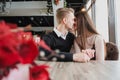 Young couple in love, man and woman on a romantic date in a cafe. Sit at a table by the window. On the table a bouquet Royalty Free Stock Photo
