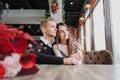 Young couple in love, man and woman on a romantic date in a cafe. Sit at a table by the window. On the table a bouquet Royalty Free Stock Photo