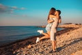 A young couple in love, a man holding a woman in his arms. In the background, the sea and the beach. The concept of Valentine`s Royalty Free Stock Photo