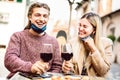 Young couple in love with open face masks having fun at wine bar outdoors - Happy millenial lovers enjoying lunch together at Royalty Free Stock Photo