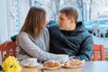 Young couple in love in outdoor cafe, spring yellow bouquet on the table, coffee, croissants Royalty Free Stock Photo