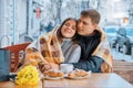Young couple in love in outdoor cafe under plaid, spring yellow bouquet on the table, coffee, croissants Royalty Free Stock Photo