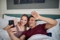 A young couple in love posing for a selfie in the bed at a hotel room. Couple, love, hotel, together Royalty Free Stock Photo