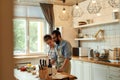 Young couple in love preparing the dough for making pizza with vegetables at home. Man and woman wearing apron, cooking Royalty Free Stock Photo