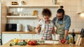 Young couple in love preparing the dough for making pizza with vegetables at home. Man and woman wearing apron, cooking Royalty Free Stock Photo