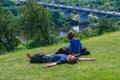 Young couple in love resting on the green hill. People relaxed in the park.