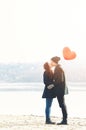 Young couple in love, at the riverside, with a red balloon Royalty Free Stock Photo