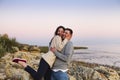 Young couple at rocky seacoast in sunset
