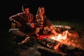 Young couple in love on romantic date at evening playing on guitar by the fire. Royalty Free Stock Photo