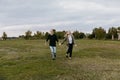 Young Couple in Love Running in a Big Open Outdoor Field in the Spring Holding Hands and Laughing Royalty Free Stock Photo