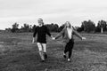 Young Couple in Love Running in a Big Open Outdoor Field in the Spring Holding Hands and Laughing Royalty Free Stock Photo