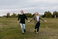 Young Couple in Love Running in a Big Open Outdoor Field in the Spring Holding Hands and Laughing Royalty Free Stock Photo