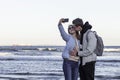 Young couple in love on sea shore taking selfie with mobile phone. Portrait of a romantic couple in love hugging and kissing by th Royalty Free Stock Photo