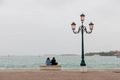 Young couple in love sitting on a bench by the sea on the waterfront of the Venice, Italy Royalty Free Stock Photo