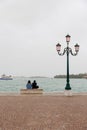 Young couple in love sitting on a bench by the sea on the waterfront of the Venice, Italy Royalty Free Stock Photo