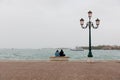 Young couple in love sitting on a bench by the sea on the waterfront of the Venice, Italy Royalty Free Stock Photo