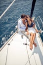 A young couple in love sitting on the bow of the yacht and enjoying romantic moments while ride on the sea. Summer, sea, vacation Royalty Free Stock Photo