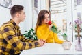 Young couple in love sitting in cafe celebrating their honymoon, man brought a red rose for his beautiful young woman,. Royalty Free Stock Photo