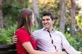 Young couple in love sitting together on a bench, the man looking at the woman, smiling Royalty Free Stock Photo