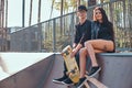 Couple in love sitting together on a ramp in the skate park at the summertime Royalty Free Stock Photo