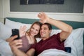 A young couple in love taking a selfie in the bed at a hotel room. Couple, love, hotel, together Royalty Free Stock Photo