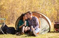 Young couple in love with thermos in hand kissing in front of the tent