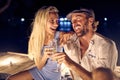 A young couple in love are toasting while enjoying wine at night out at the bar on the river bank. Night, love, bar, river Royalty Free Stock Photo