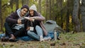 Young couple in love travelers sits in nature resting drinking tea from thermos enjoy hot drink resting talking smiling Royalty Free Stock Photo