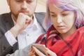 Young couple in love while traveling monitoring their stock prices remotely with smart phone. Selective focus Royalty Free Stock Photo