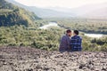 Young couple in love traveling together in mountains. Happy hipster man and girl sitting together on the top of mountain