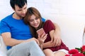 Couple in love using smartphone together sitting on white couch in the living room at home. Handsome man hold cell phone in Royalty Free Stock Photo