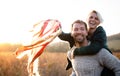 Young couple in love on a walk in autumn forest, holding hand ribbon kites.