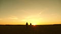 Young couple in love walking across the field holding hands. girl and man go to the sunset. happy family walks in the Royalty Free Stock Photo