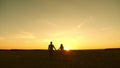 Young couple in love walking across the field holding hands. girl and man go to the sunset. happy family walks in the Royalty Free Stock Photo