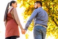 Young couple in love walking in the autumn park holding hands looking in the sunset Royalty Free Stock Photo