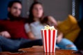 A young couple in love watching television at night romantic date night lying on the couch eating popcorn Royalty Free Stock Photo