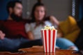 A young couple in love watching television at night romantic date night lying on the couch eating popcorn Royalty Free Stock Photo
