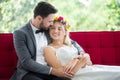 young couple in love Wedding Bride and groom lying down on red sofa looking at each other and embracing together . Newlyweds . Royalty Free Stock Photo