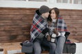 Young couple in love in the woods basking under a blanket. They drink tea from a thermos Royalty Free Stock Photo