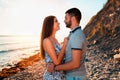 A young couple of lovers embrace and pose against the background of the beach, sea and sunset. Side view. The concept of Valentine Royalty Free Stock Photo