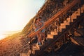 A young couple of lovers embrace standing on the stairs and pose against the background of the sea and sunset. The concept of