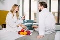 Young couple lovers in white hotel bathrobes eating fresh fruits and drinking champagne in bed Royalty Free Stock Photo