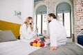 Young couple lovers in white hotel bathrobes eating fresh fruits and drinking champagne in bed Royalty Free Stock Photo