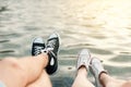 Young couple lying on the beach. Legs with sneakers near water.