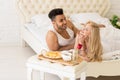 Young Couple Lying In Bed Eat Breakfast Morning With Red Rose Flower, Happy Smile Hispanic Man And Woman Royalty Free Stock Photo