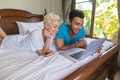 Young Couple Lying In Bed, Happy Smile Hispanic Man And Woman Using Laptop Computer Royalty Free Stock Photo